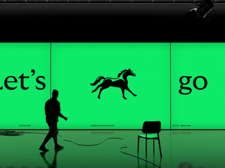 Conference backdrop showing a galloping black horse logo between "Let's" and "go".